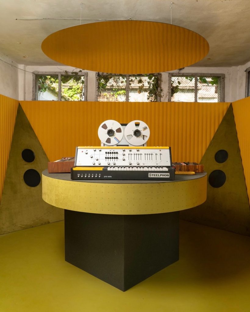 Som e design no projeto acústico da Slalom Acoustics, em um ambiente amarelo com paredes curvas.